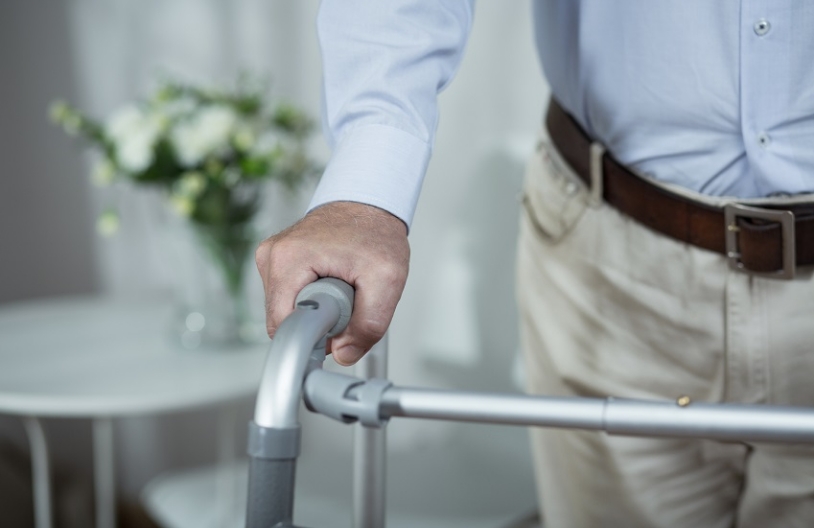 Hand of elderly man on walker handle.